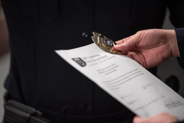 Hands holding a paper and a police badge