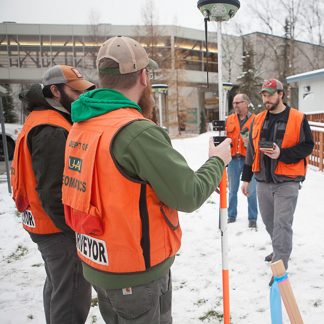 Students standing outdoors using land surveying tools
