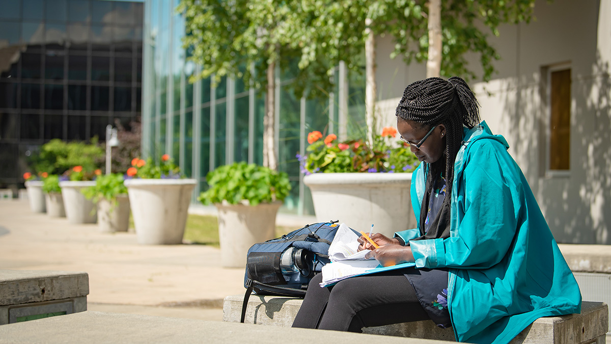A UAA student studies outdoors on one of the benches