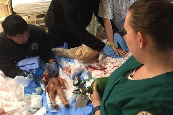healthcare professionals gathered around a baby manikin