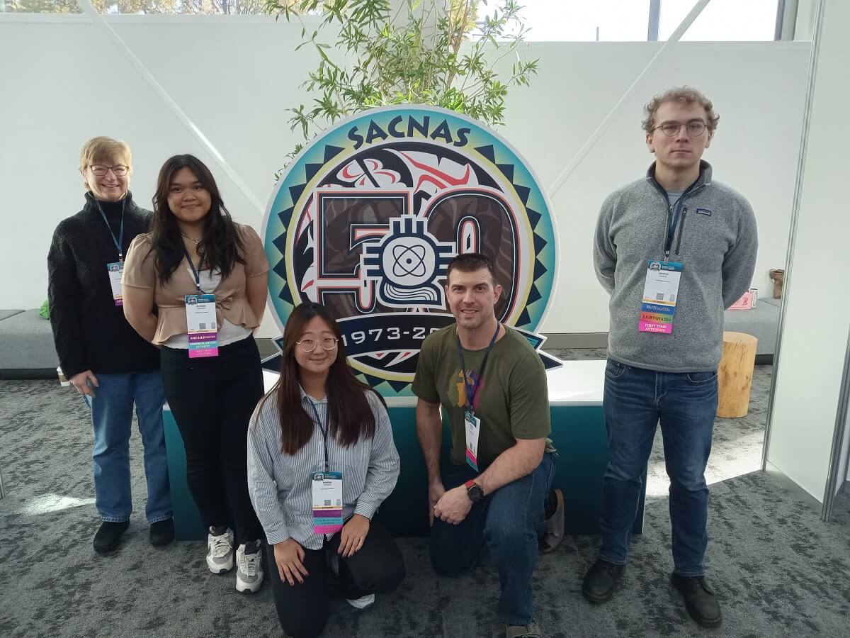 Biomed U-RISE student pose in front of SACNAS sign at the conference