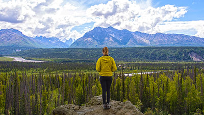 A student looking out on an Alaskan vista with mountains in the background
