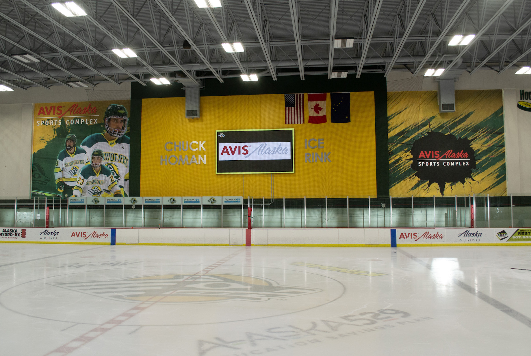 AASC Hockey Rink with 2 Large Format Prints. One print has a mural with 3 hockey players and the other mural has a design with Avis Alaska logo.