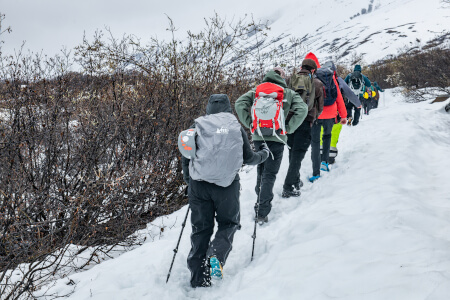 Students hike through snow up to a glacier on a research trip 