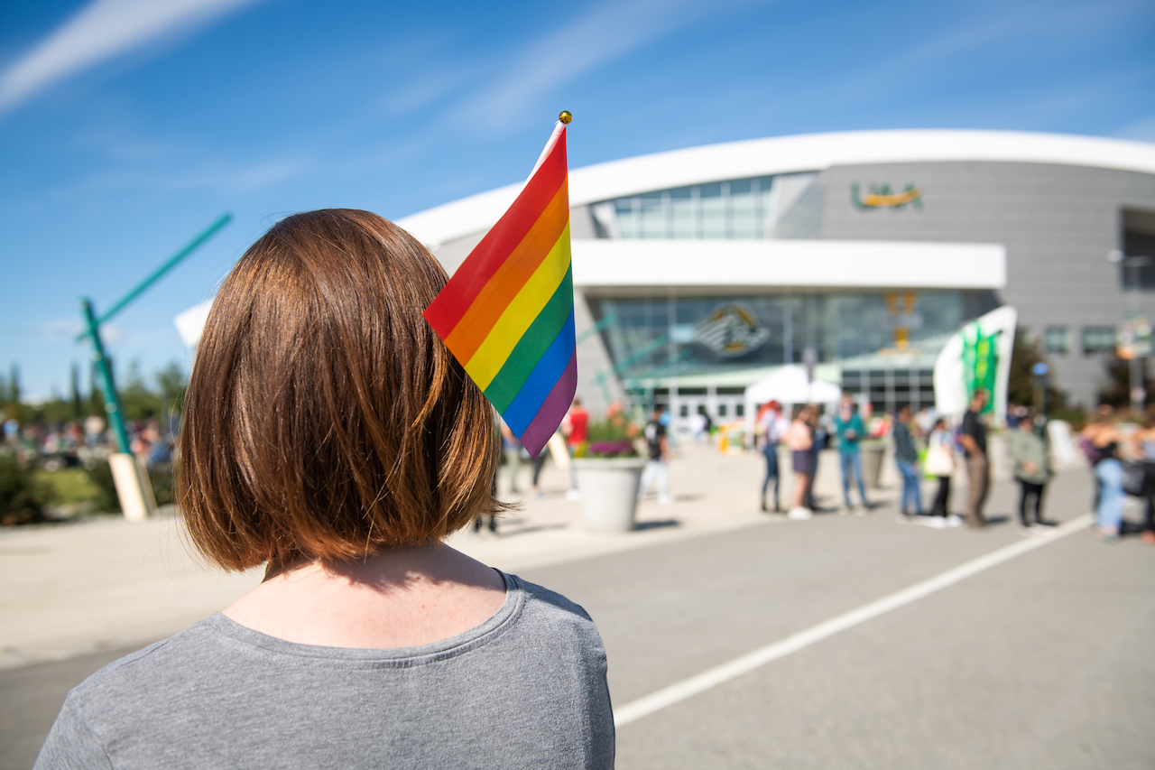 UAA student holds a rainbow flag during a festival at the Alaska Airlines Center plaza.