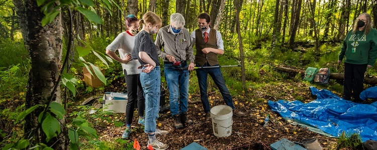 students studying bear skeleton in forest