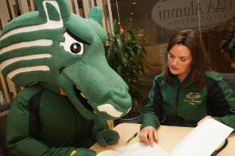 Mascot and woman looking at papers on desk