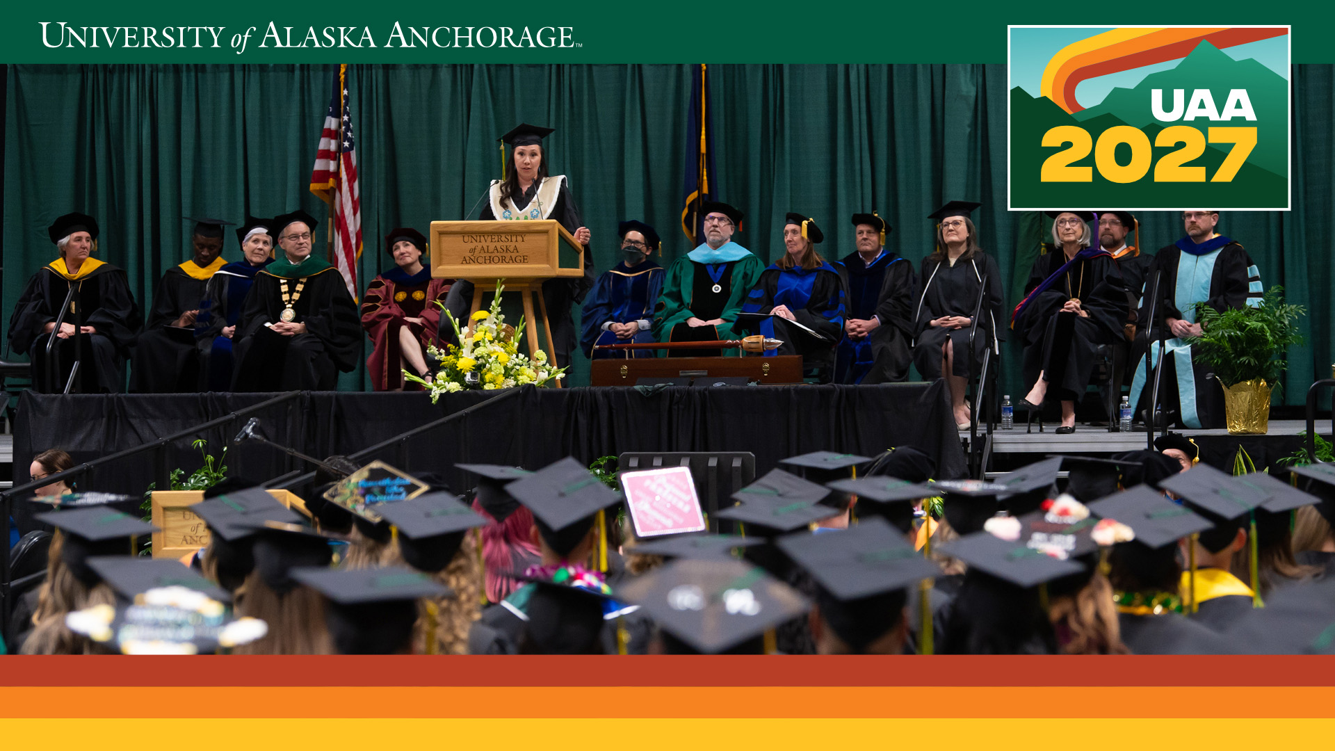 UAA 2025 desktop background preview — Student speaking at commencement
