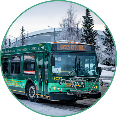 Anchorage city bus wrapped in UAA advertisement with sign saying, "Masks Required."