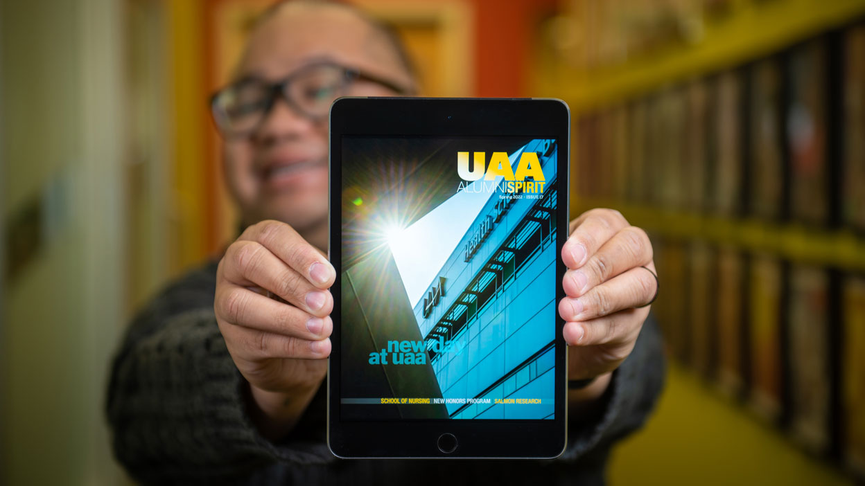 man holding up tablet with digital magazine cover