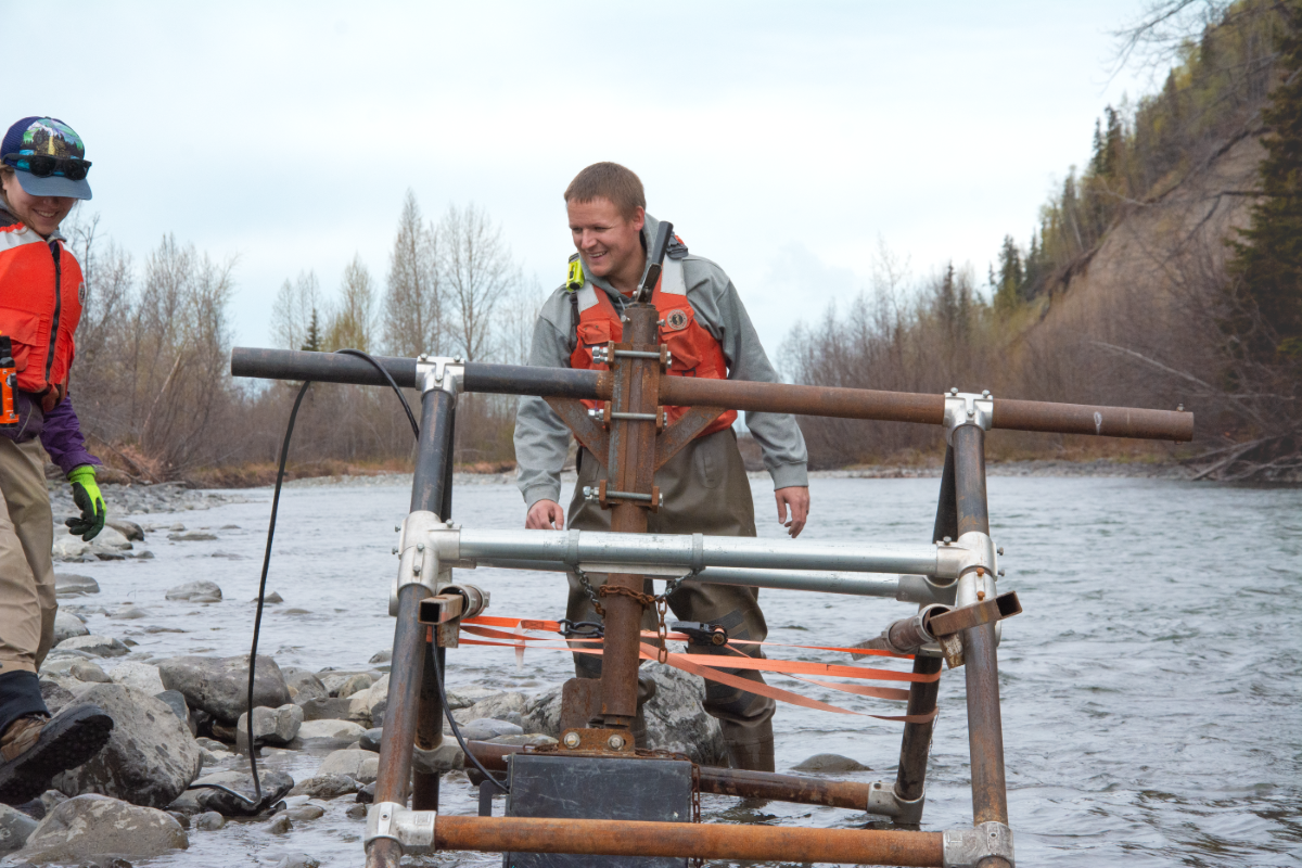A man stands behind a metal monitoring device in a river