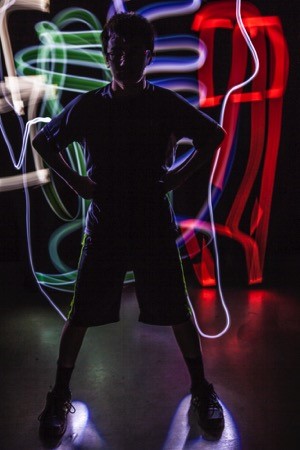 Young boy standing in the dark with neon lights behind him
