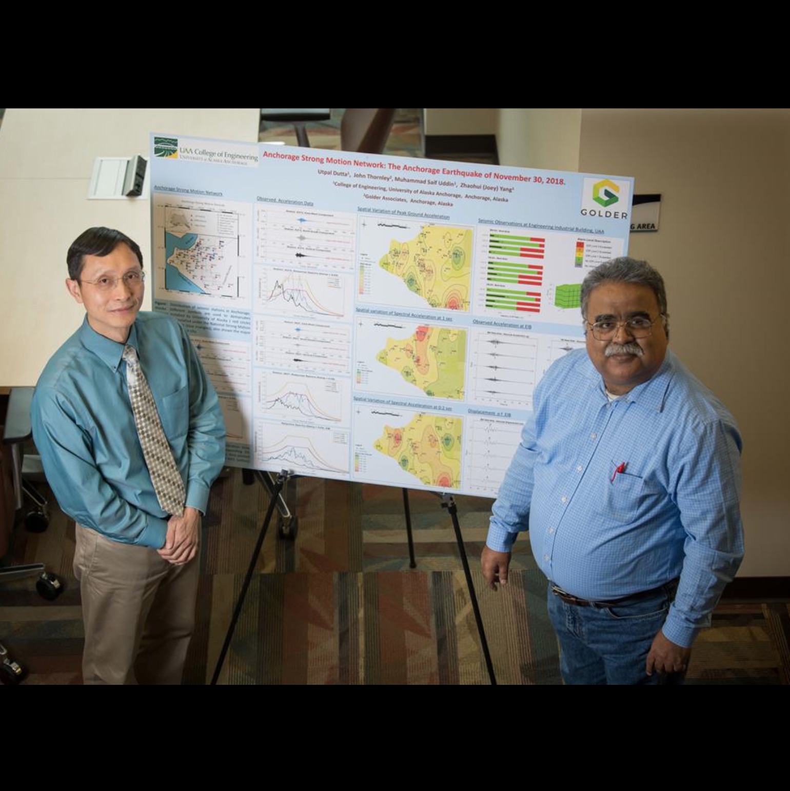 professors Joey Yang and Utpal Dutta stand before a presentation poster.