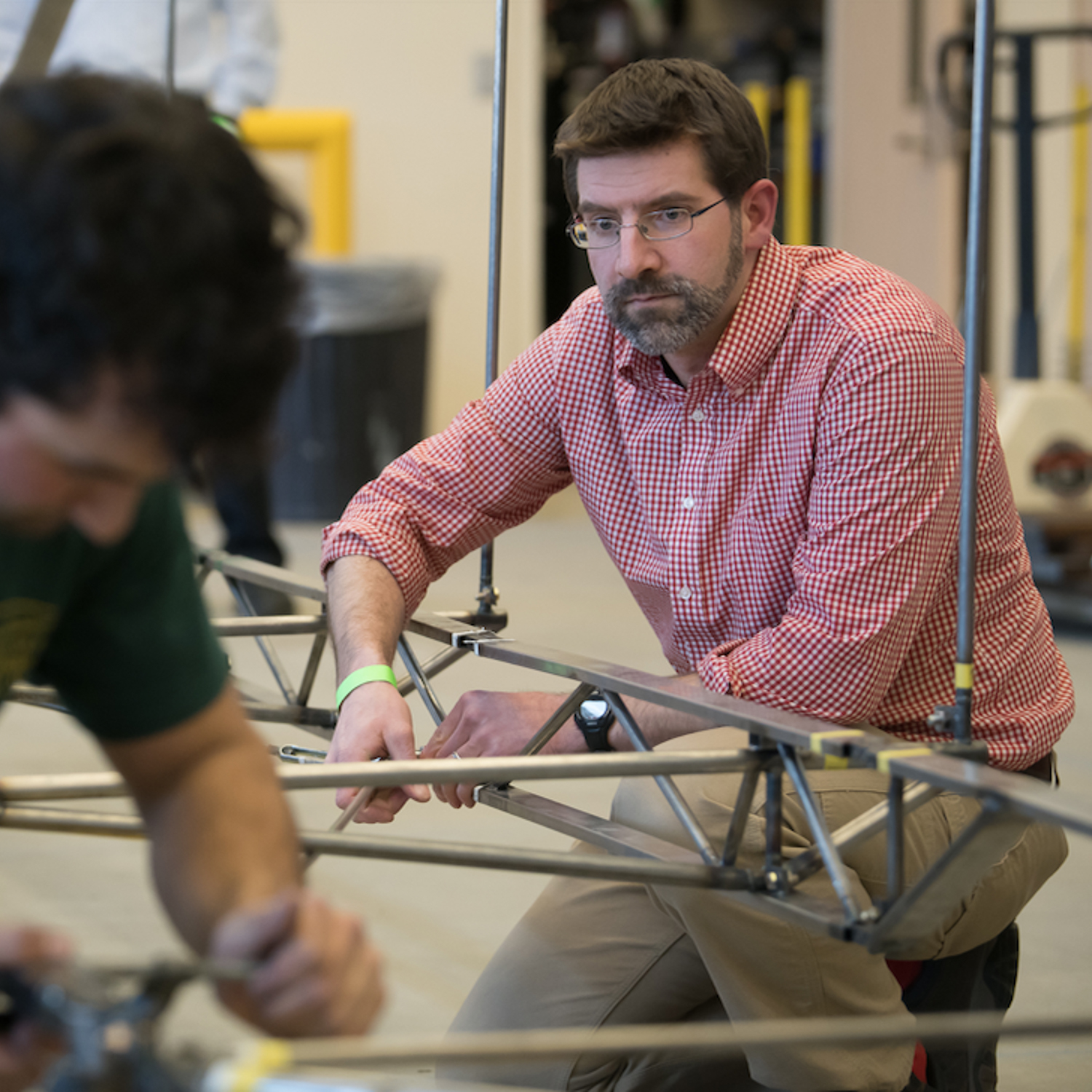 Dr. Scott Hamel working with a student assembling a steel bridge.