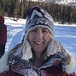 kathy crafton smiles at the camera with a snow hat and coat in front of snowy background