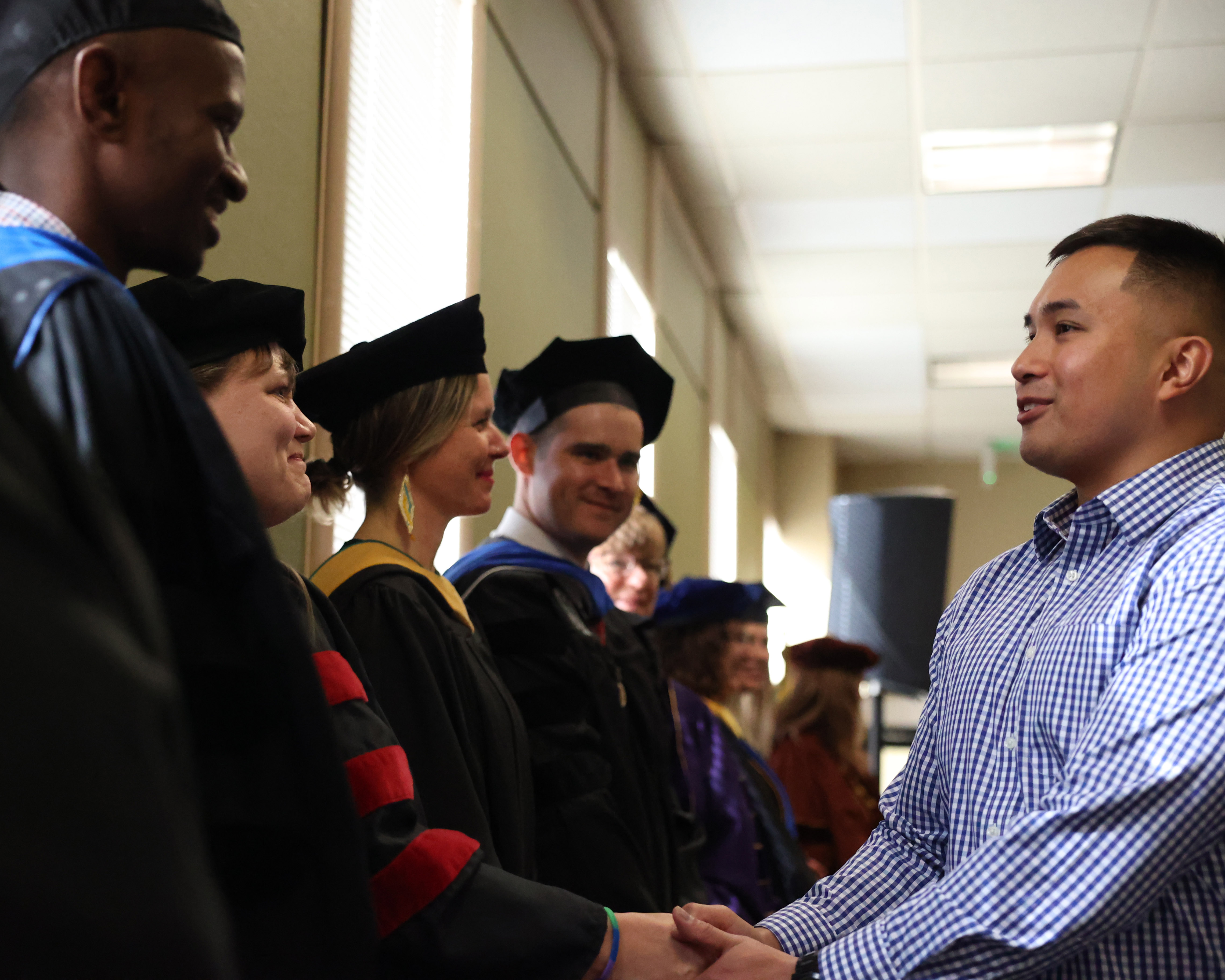 student shaking hands with a line of professors in cap and gown
