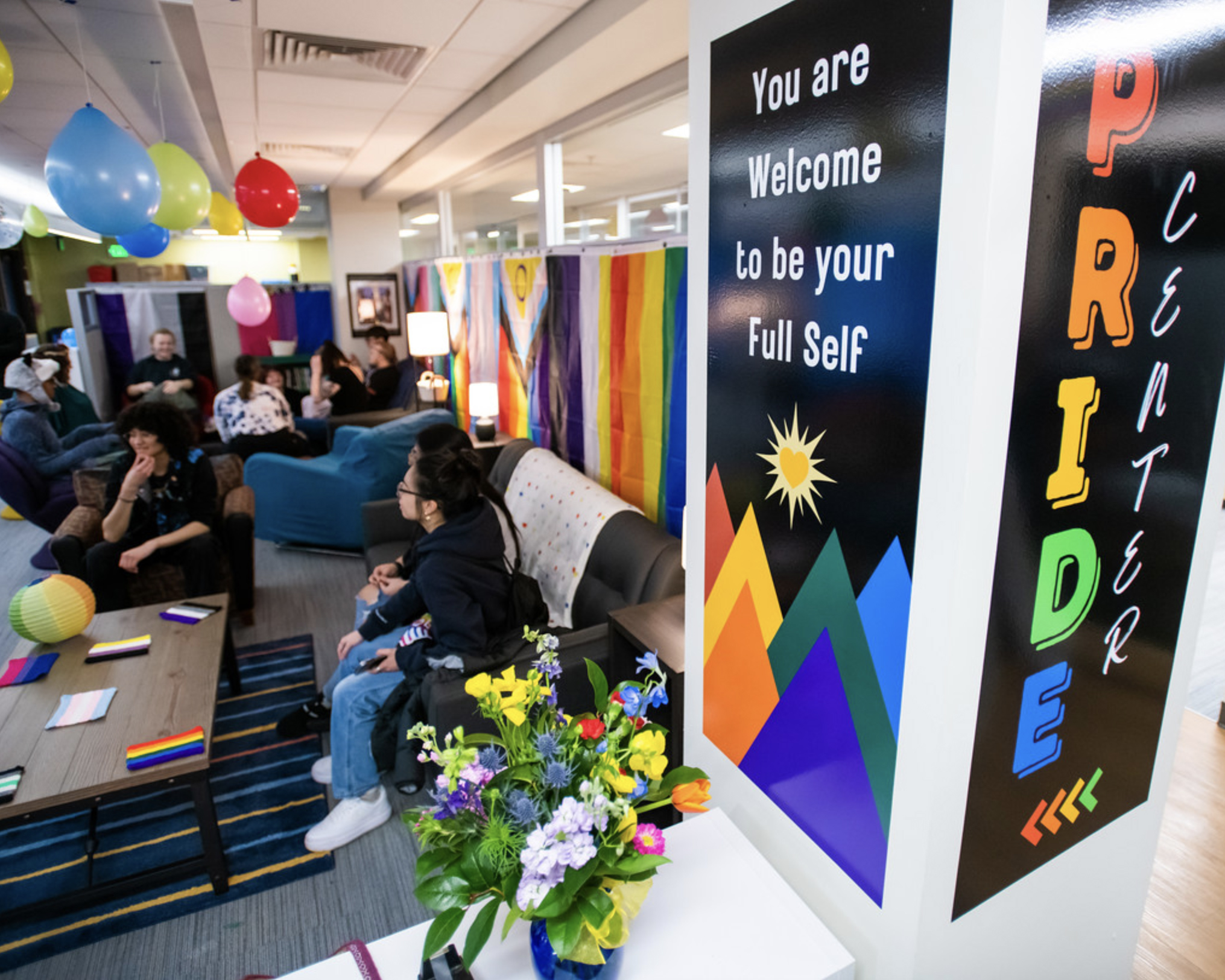 Students sitting on couch behing post that says PRIDE