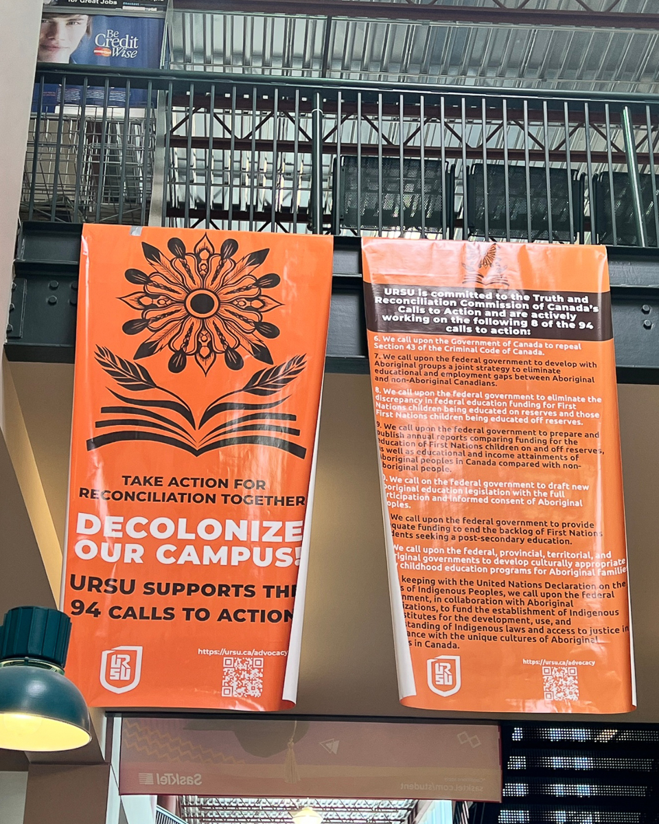 large orange banner in hallway with flower reading "decolonize our space"