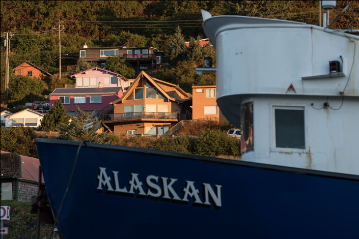 Boat that says "Alaskan" in front of houses on a hill