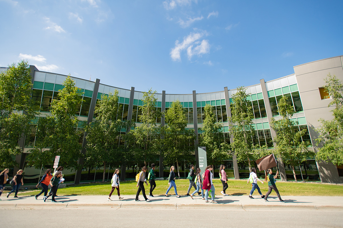 A group of UAA students walk outdoors on campus