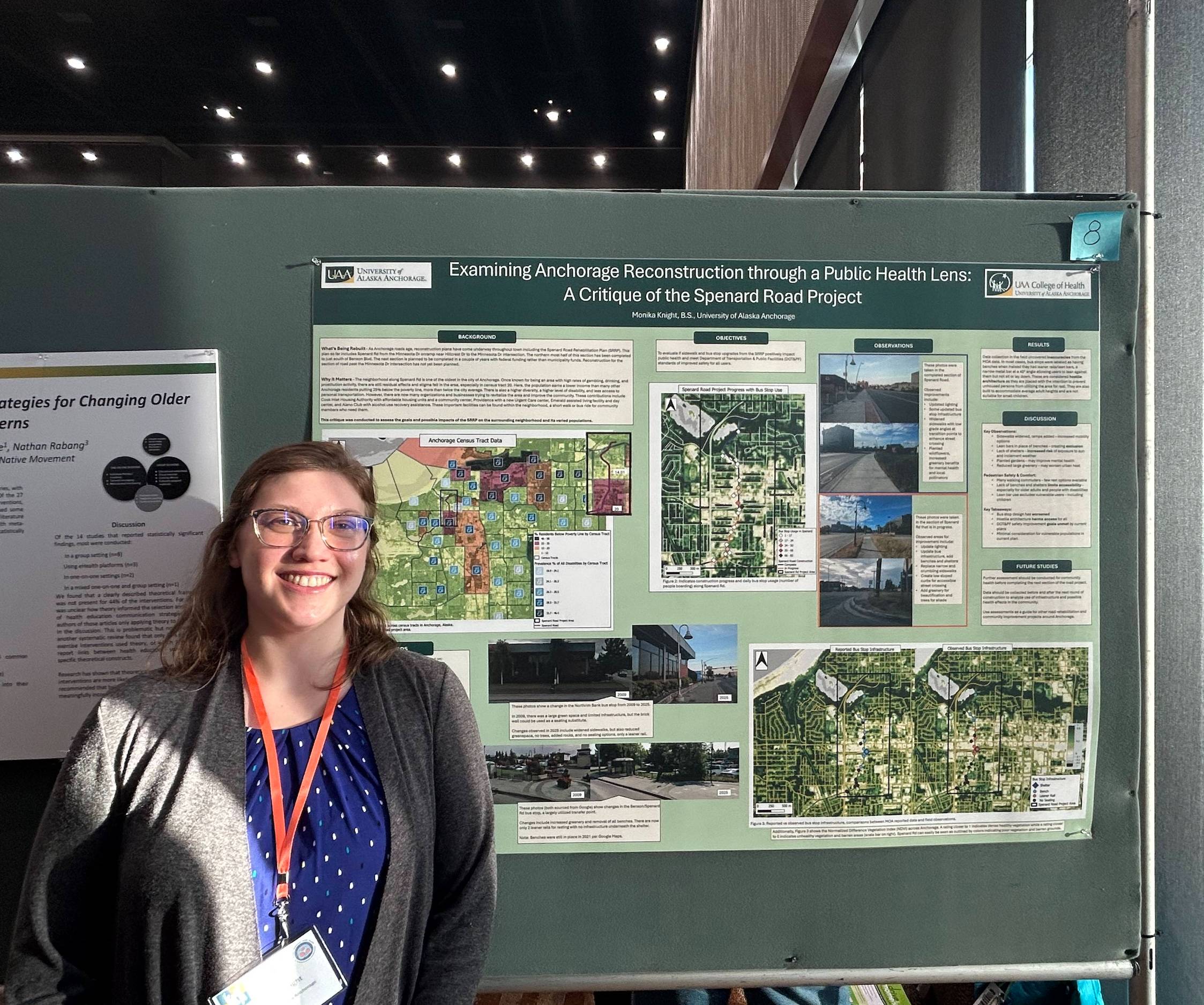 Monika Knight stands in front of her poster, titled "Examining Anchorage Reconstruction through a Public Health Lens: A Critique of the Spenard Road Project." She is smiling and wears a conference name badge. 