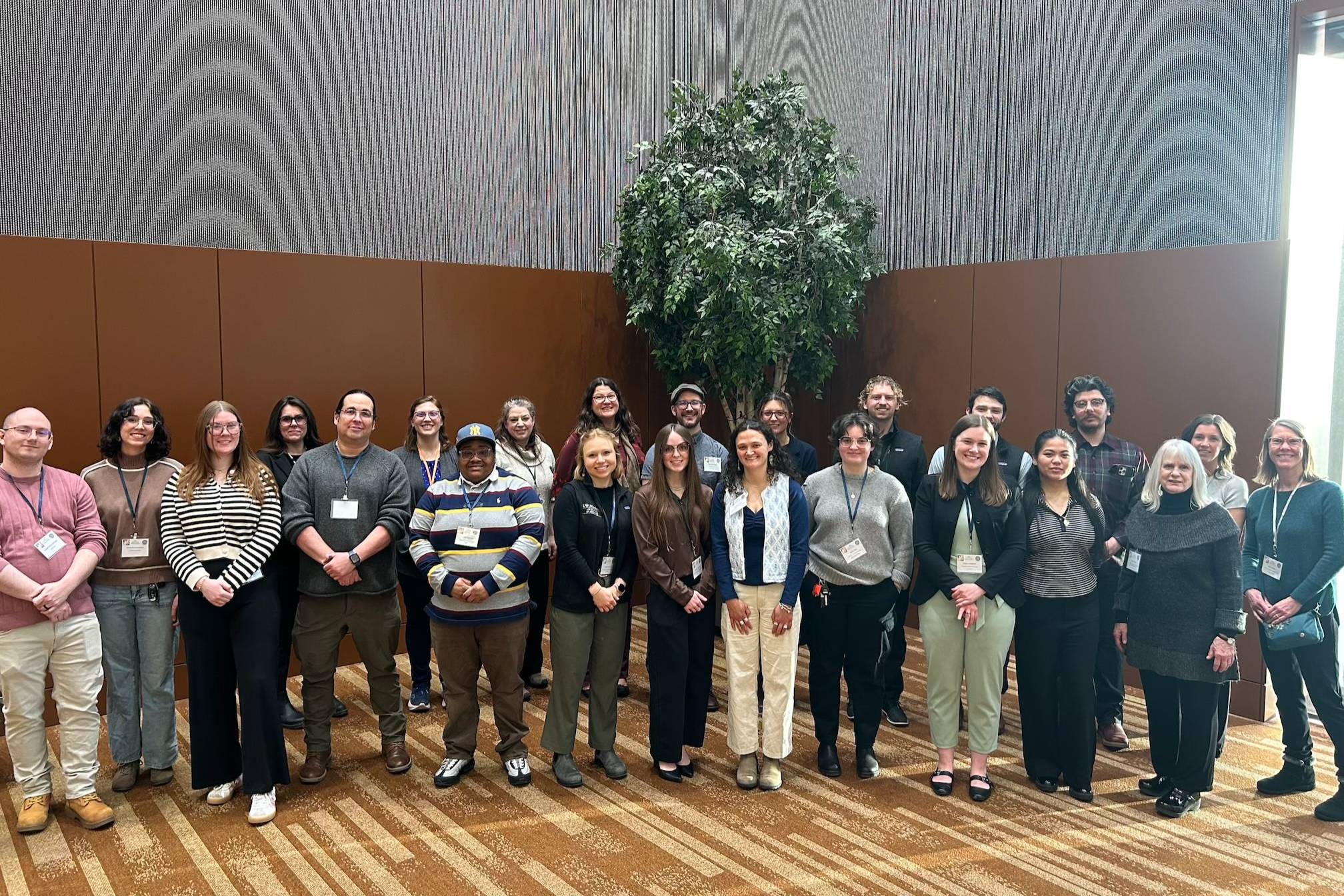 UAA faculty and students stand in a corner of the Dena'ina Convention Center room. 