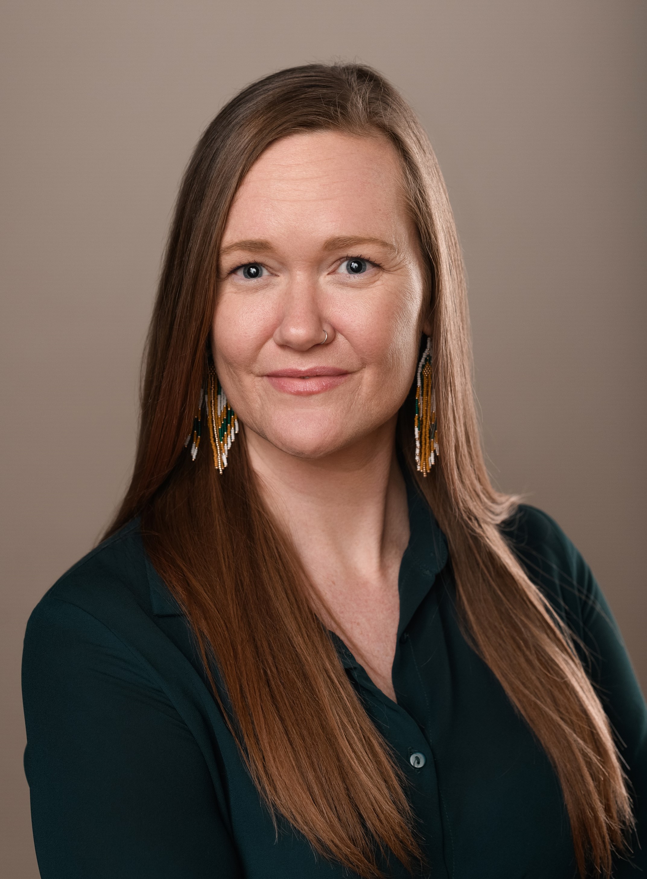 Dr. Britteny Howell's headshot shows her smiling at the camera. She is wearing a dark button-down shirt and beaded earrings.