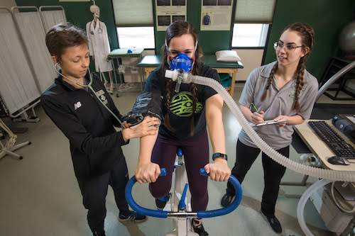 Students performing a breathing test on a stationary bike