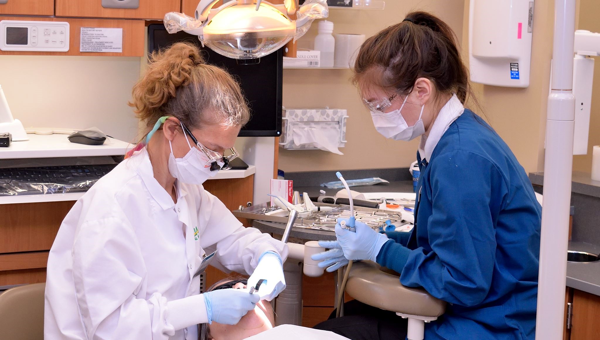 Dental student helping dentist with patient