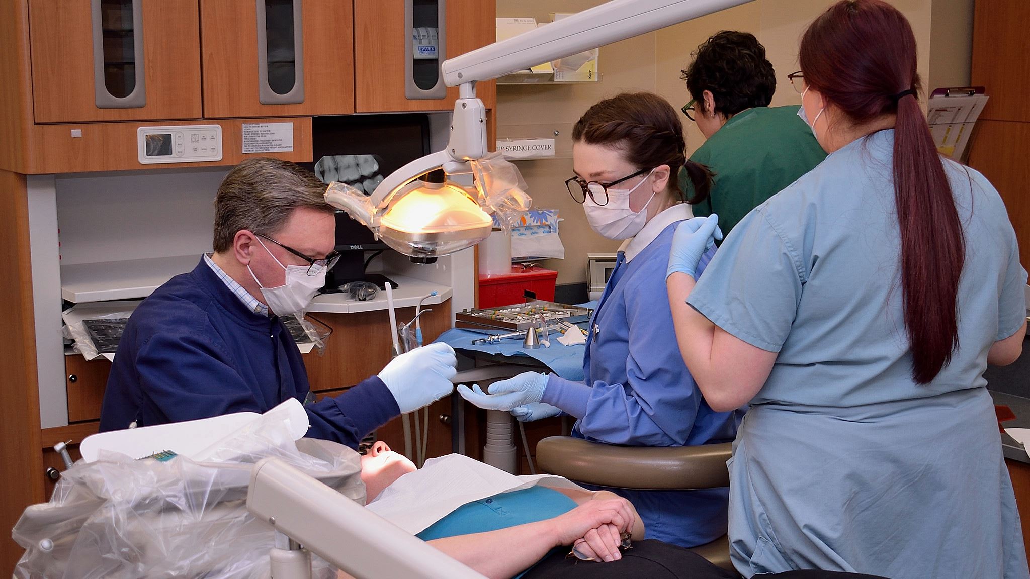 Dental students helping dentist with patient