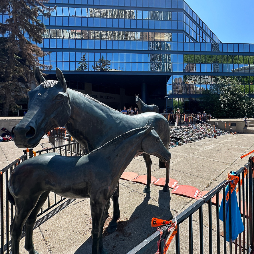 shoes piled on concrete straircase in front of metal horse sculpture