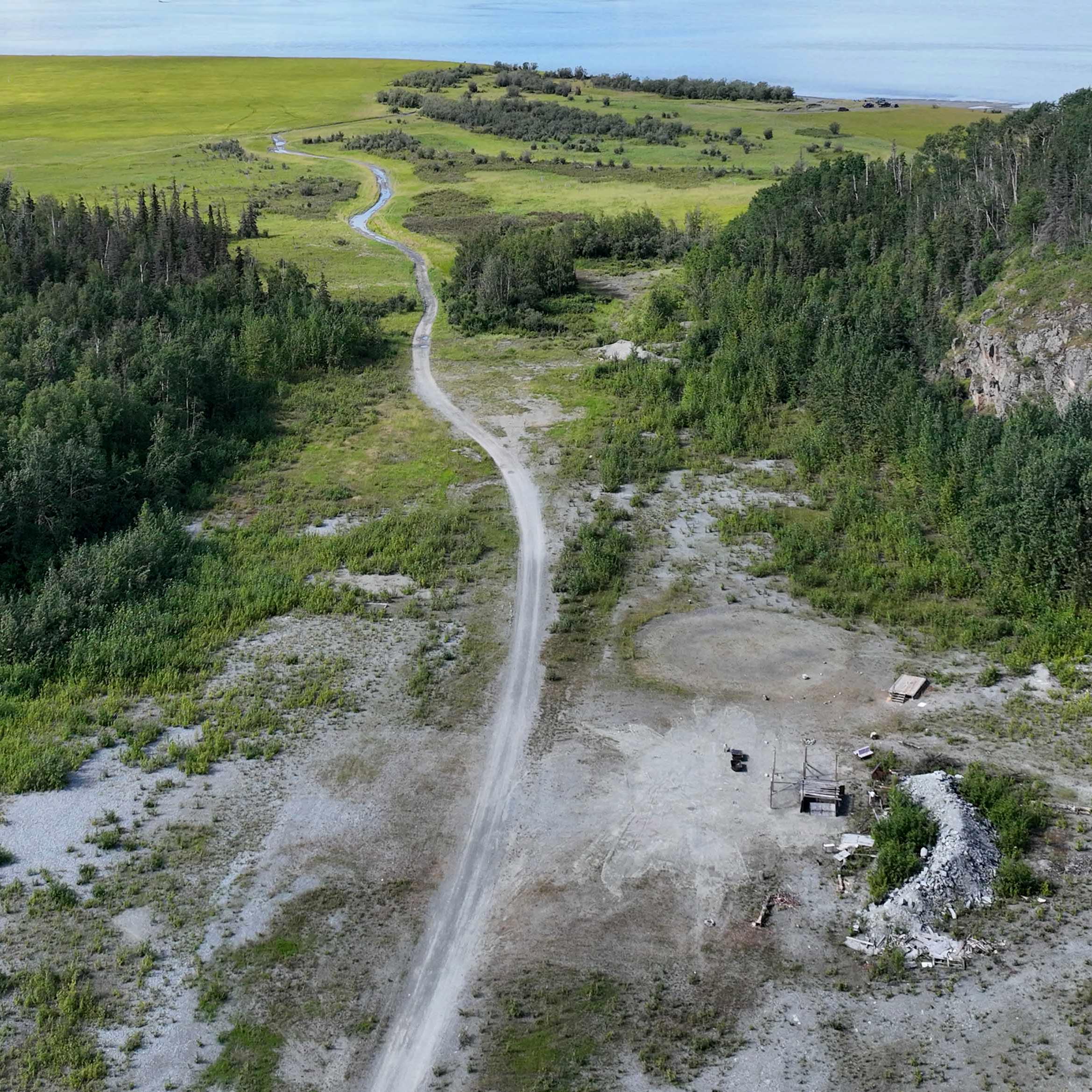 birds eye view of heavily forsested land, river, green feild