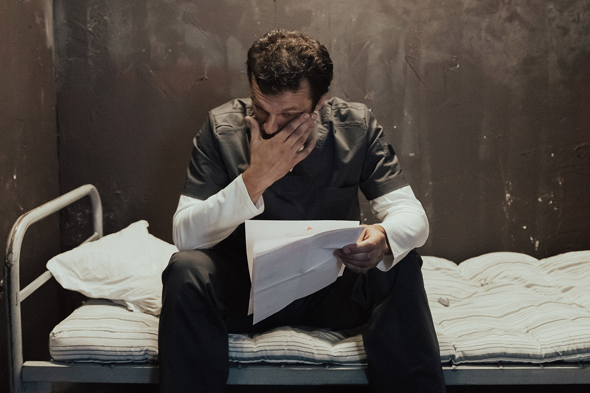 A prisoner in his cell emotionally reading a letter