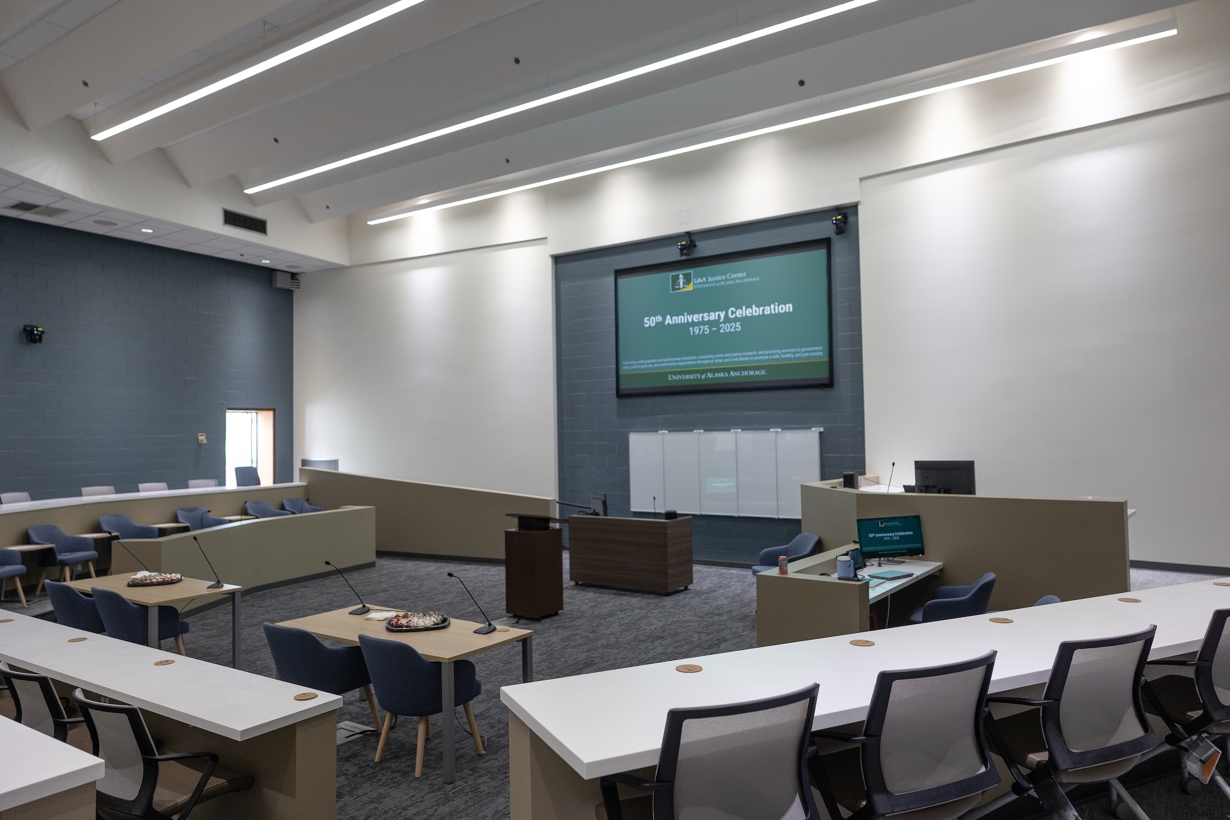 Photo taken from the back of the Havelock Classroom. It shows rows of desks, two counselor tables, a podium, judicial dais, jury box, and screen reading "50th Anniversary Celebration"
