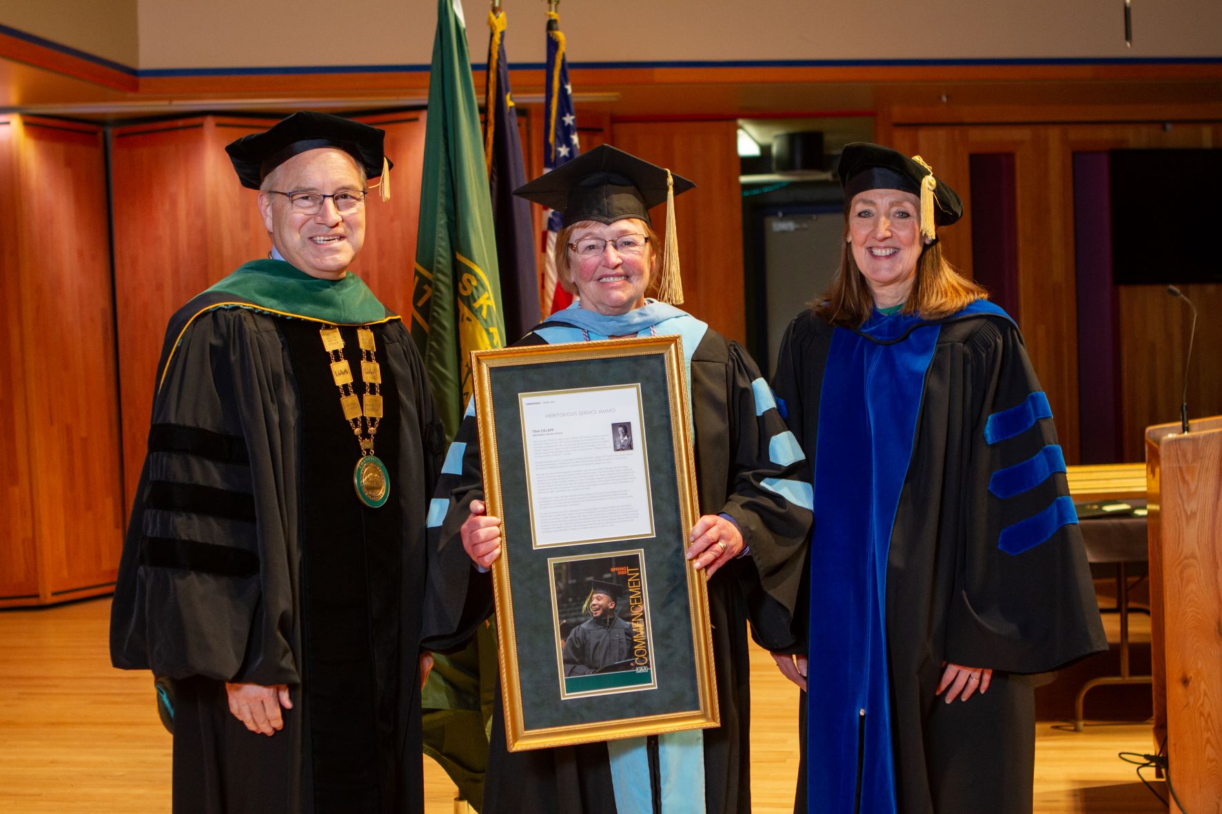 Tina DeLapp holding award and standing with Chancellor Parnell and Provost Runge