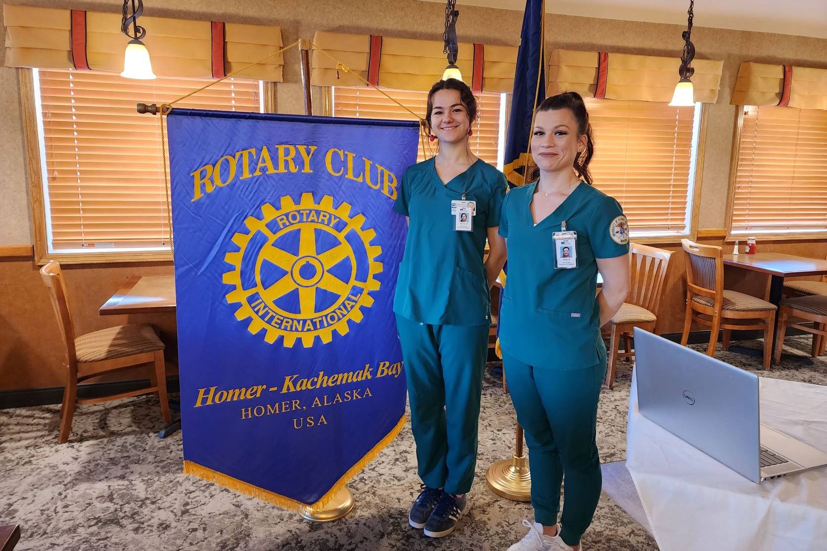 Nursing students standing in front of Rotary flag