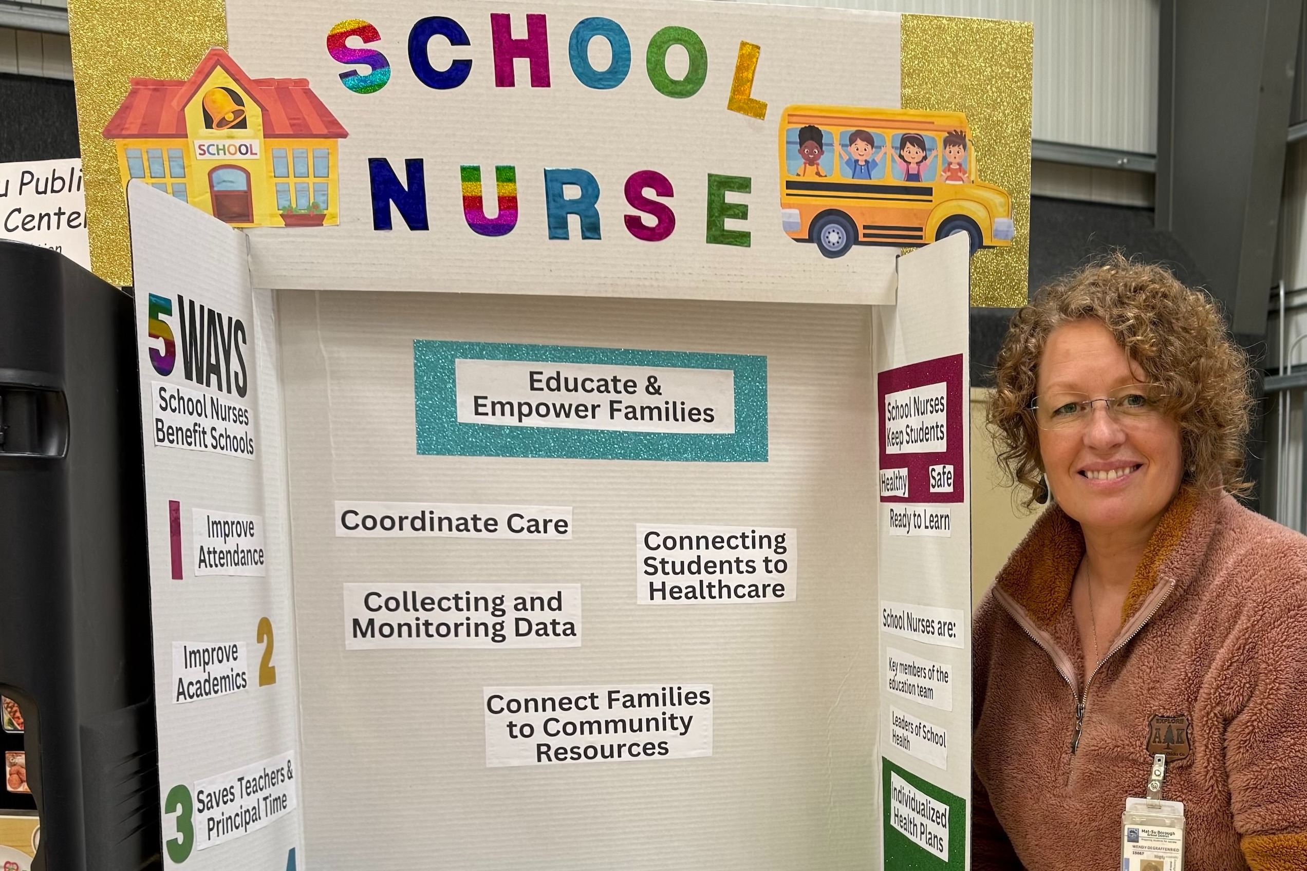 Wendy stands next to a poster titled "School Nurse" at the 2024 "Stuff the Bus" event.