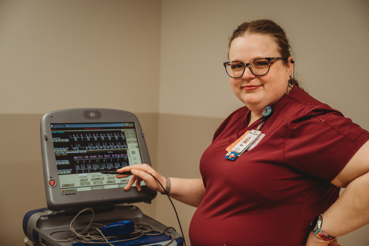 A nurse in red scrubs showing off a medical device
