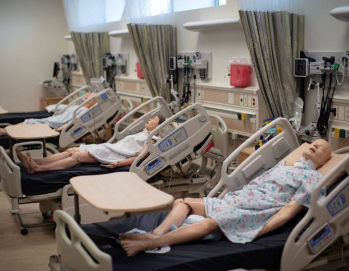 Manikins laying on hospital beds in nursing skills lab room