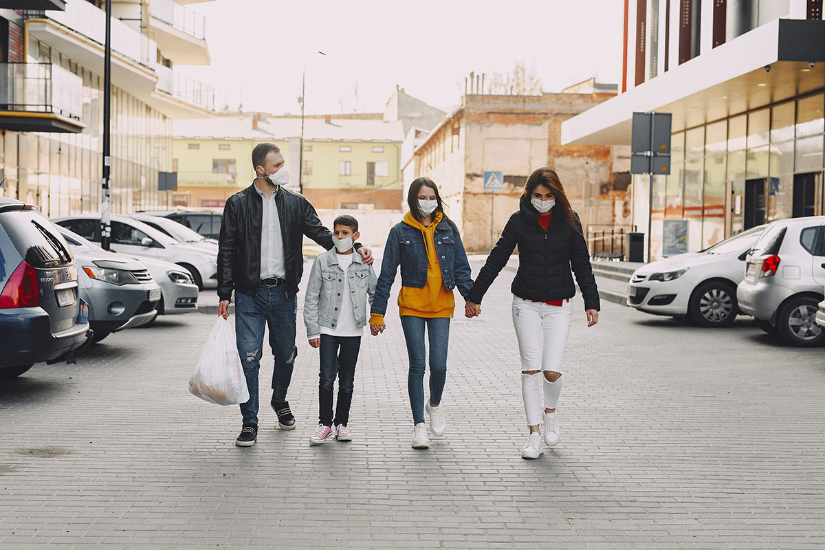 A family of four wears face masks while walking to their car after shopping