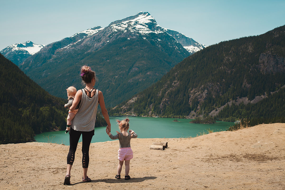 A mother with her two children look at the landscape of a mountain