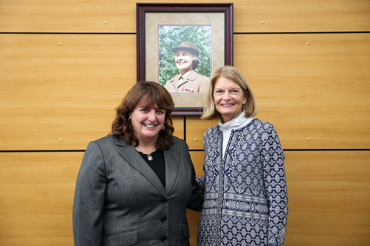 Vanessa Meade, assistant professor in the UAA School of Social Work (left), and Sen. Lisa Murkowski (right), pose in front of a portrait of Colonel Mary Louise Rasmuson at the renaming of the Alaska VA Clinic on Feb. 24. (Vicki Nechodomu/College of Health)