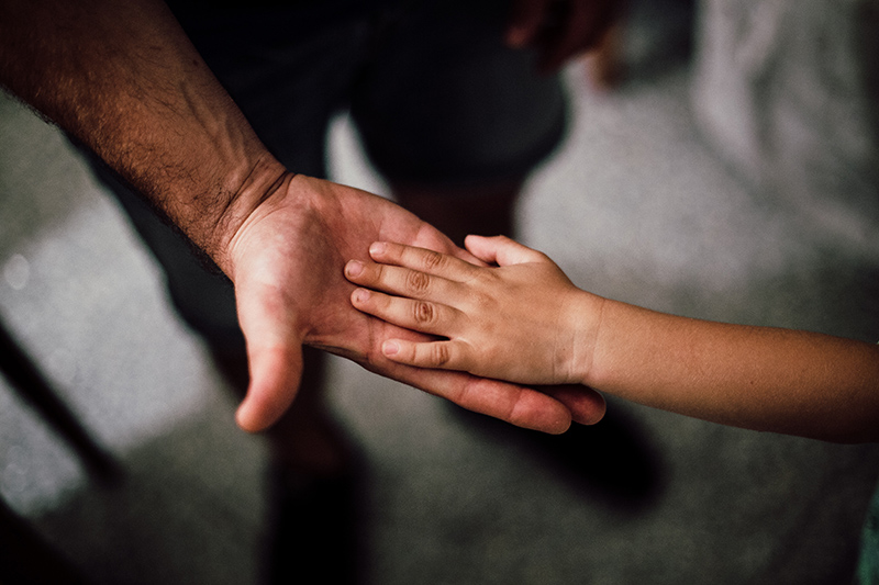 An adult holding a child's hand