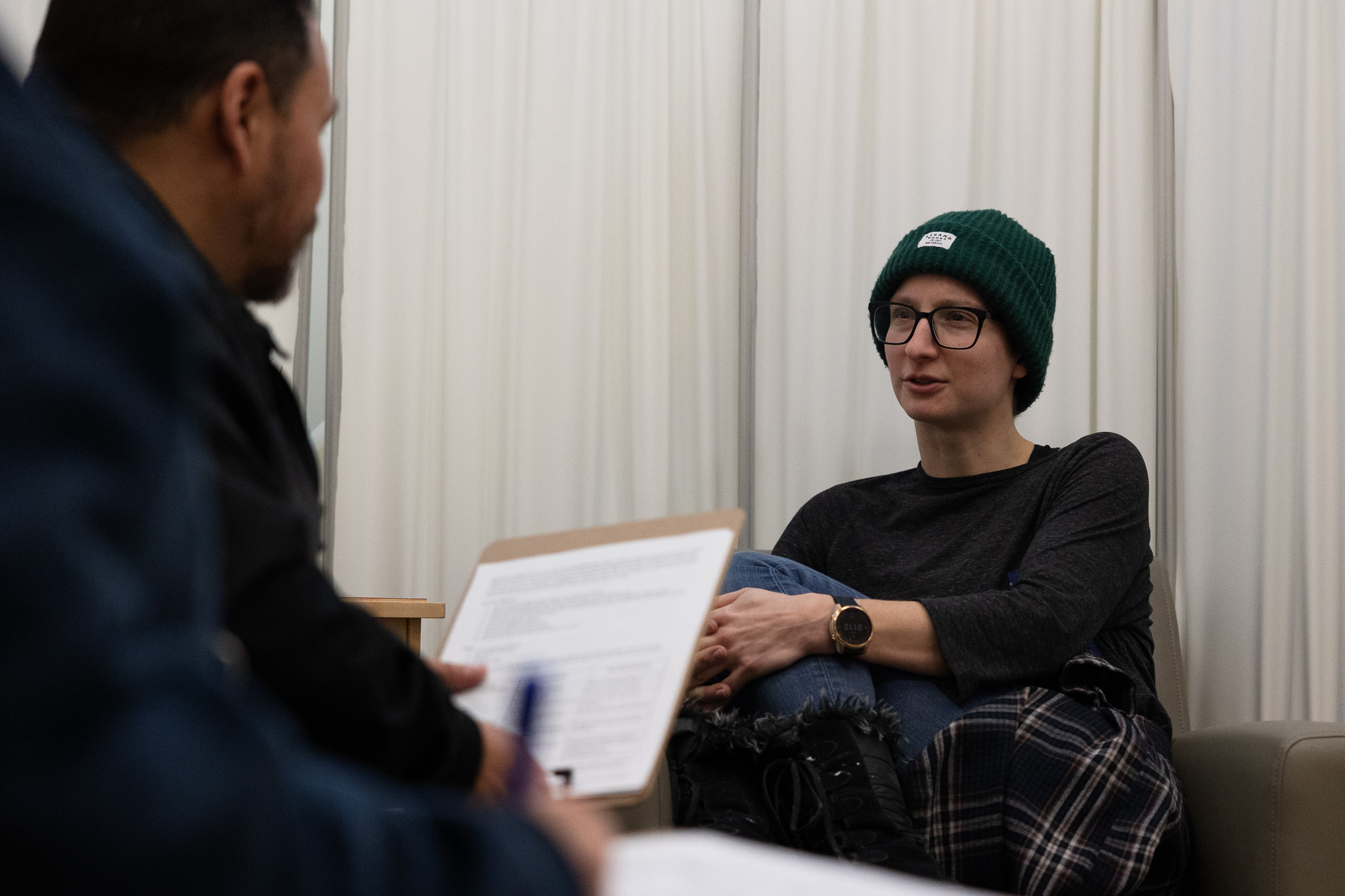 Young person in hat talking to blurry person holding clipboard