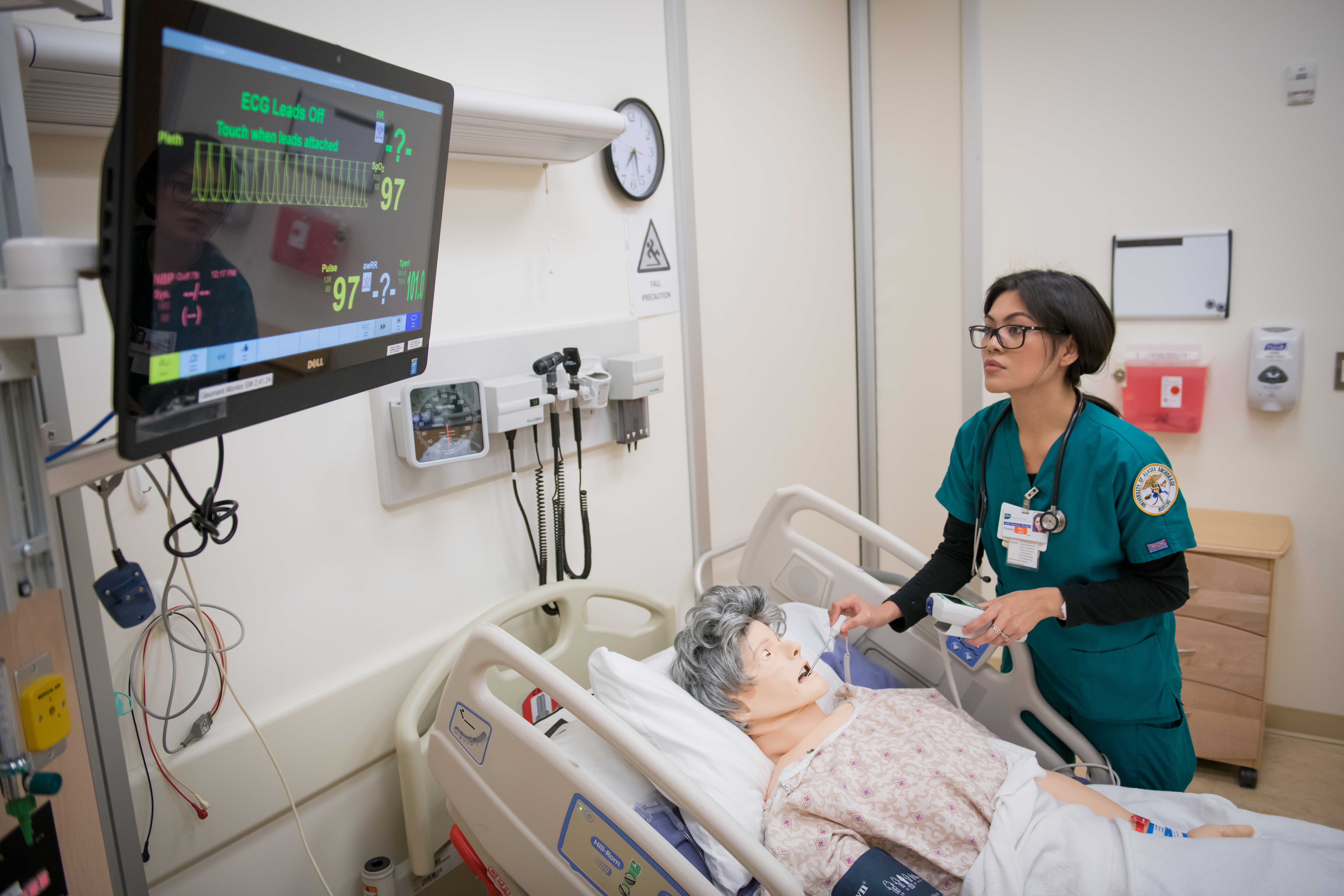 a nurse standing around manikin in hospital bed