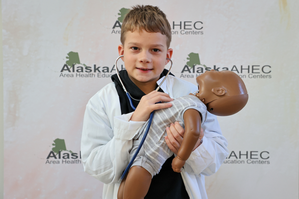 boy checking heart rate of baby manikin dressed as a doctor