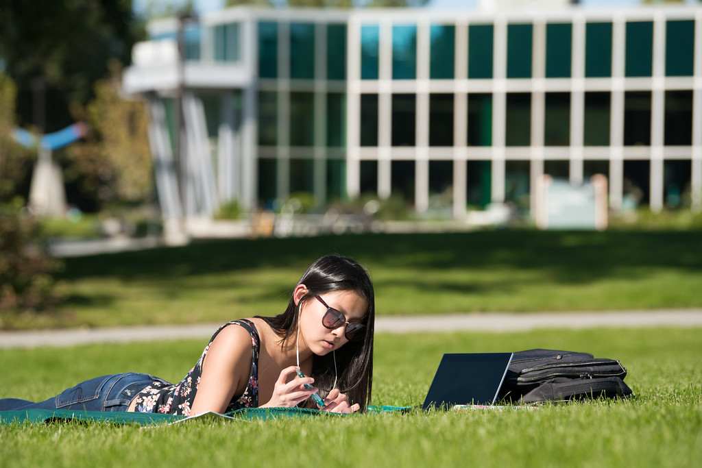 A female student lies on the grass while studying