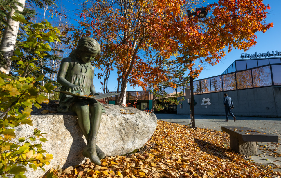 statue of girl reading in fall