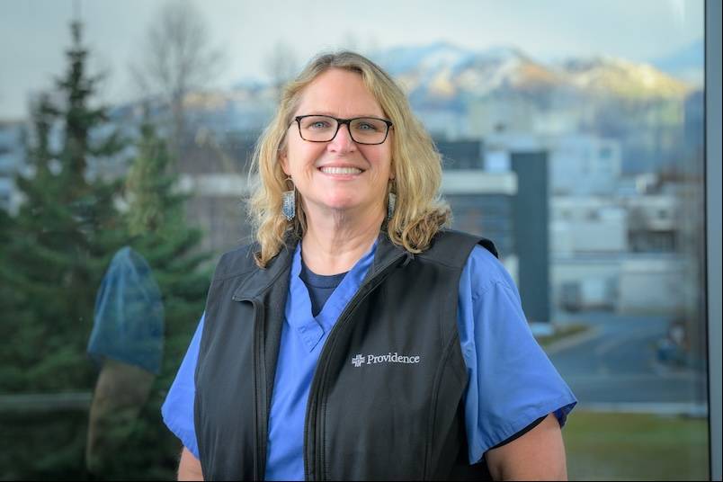 Stacy Brunquist in medical scrubs, posing on the UAA campus