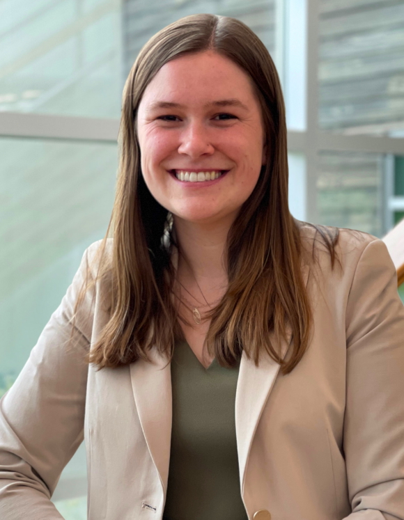 Rachel Nill smiling and posed in front of trees on the UAA campus